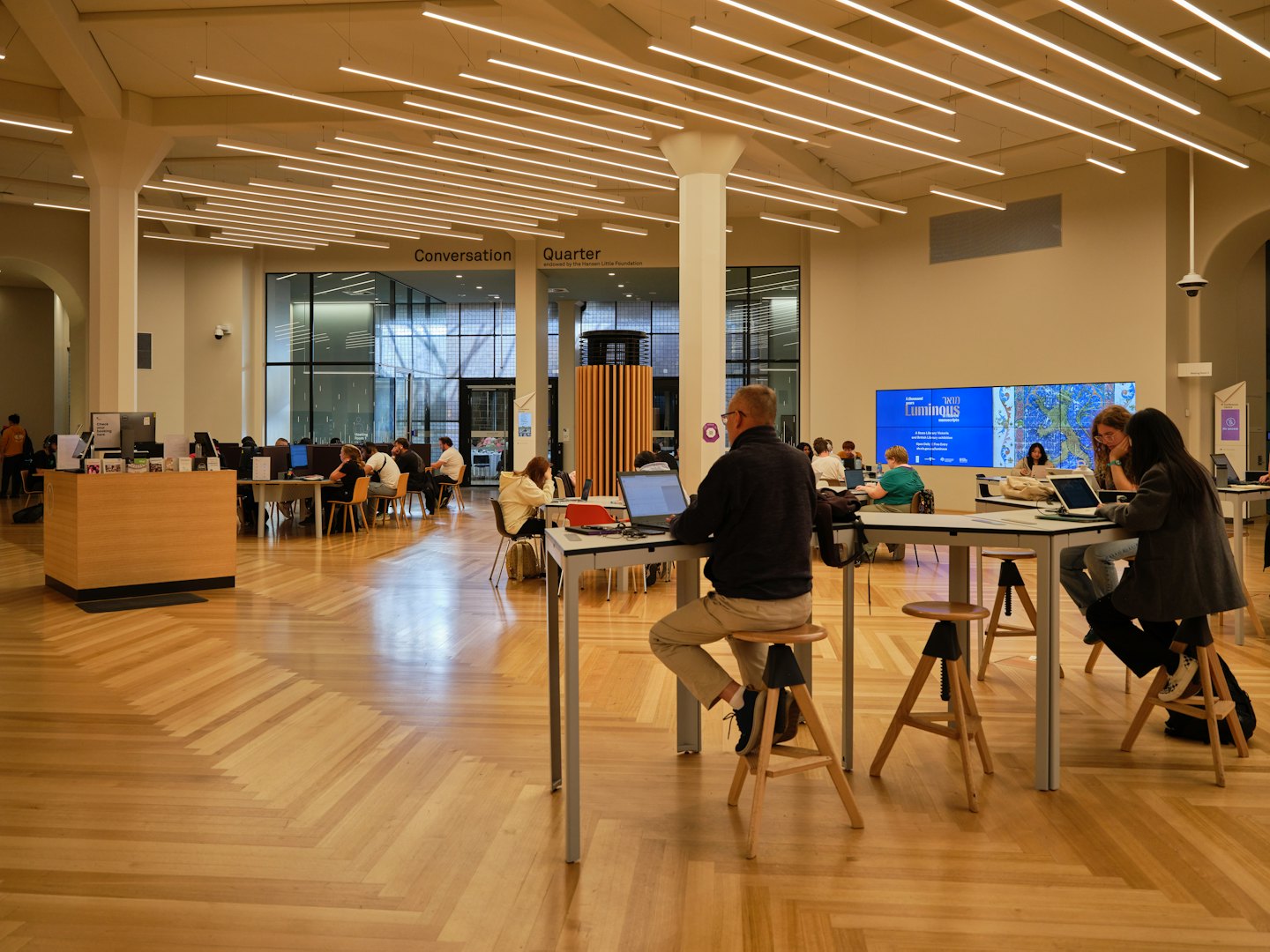 People working on laptops at tables in an open office.