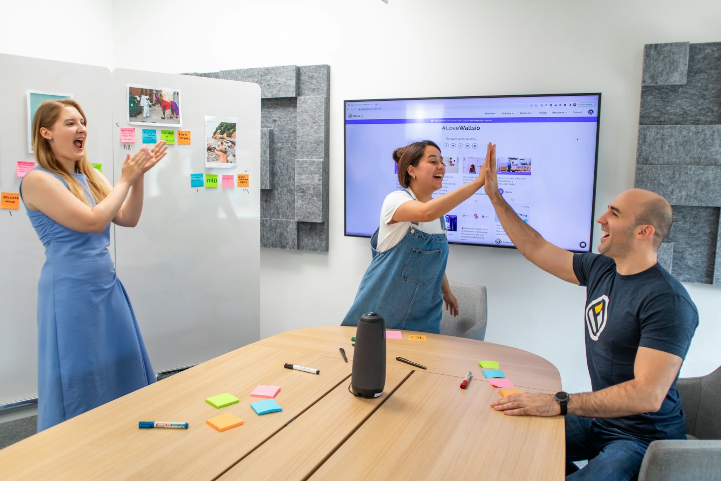 Colleagues celebrate team success in a modern office meeting room.