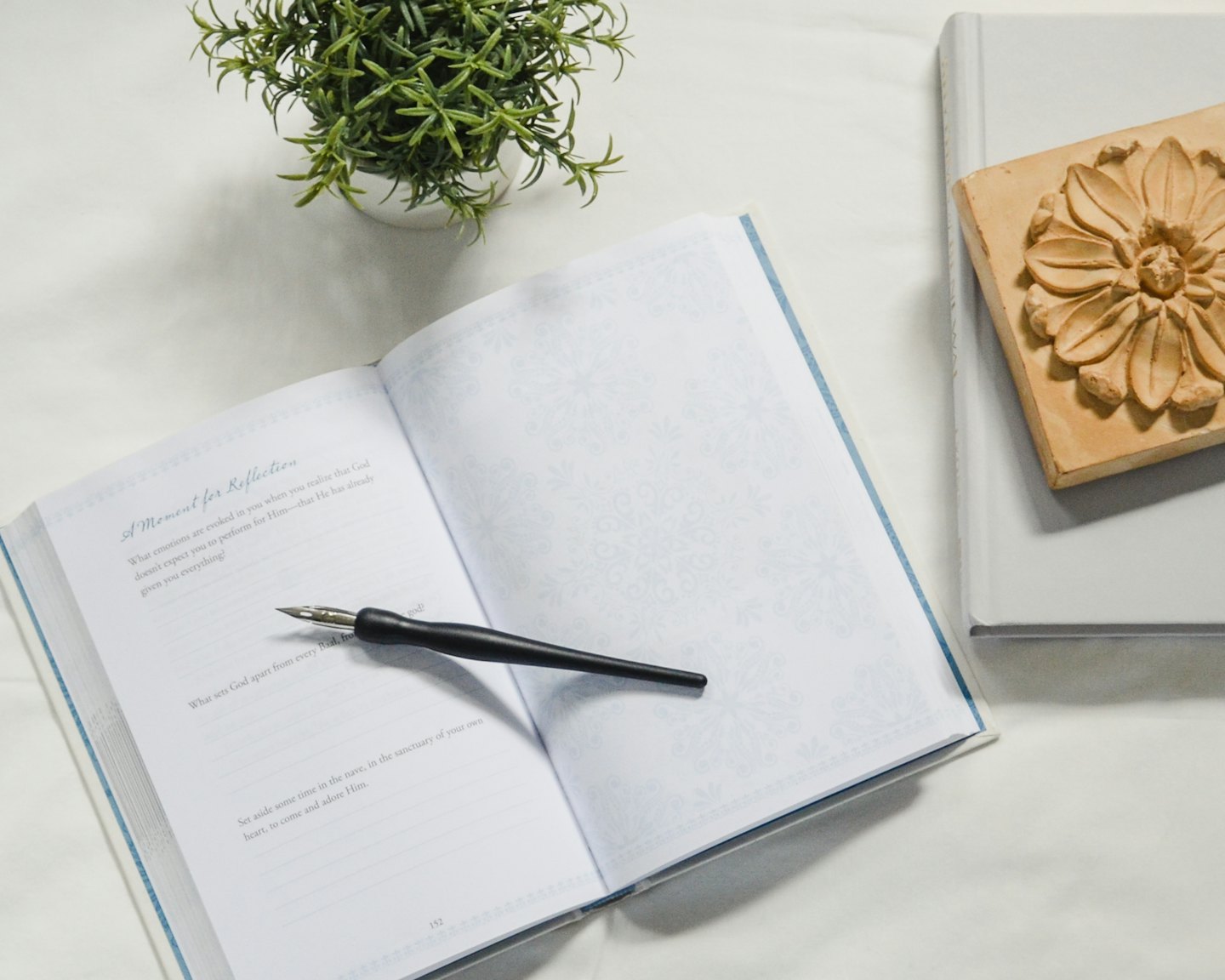 An open journal with a dip pen rests on a white surface.